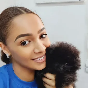 Flora, groomer at Pawfect Pets, holding a small black puppy